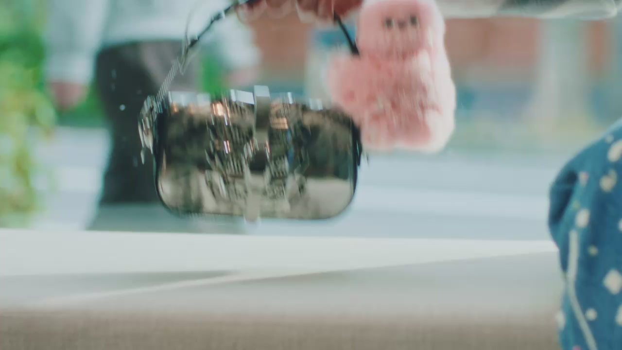 A pink mirumi clipped to a bag, moving as its owner walks